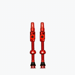 Two red Muc-Off Big Bore Lite tubeless Presta valves on white background