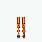 Pair of orange Muc-Off Big Bore Hybrid Tubeless Presta Valves on white background