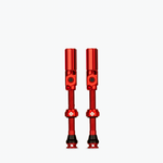 Pair of red Muc-Off tubeless presta valves on white background