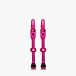 Two pink Muc-Off Big Bore Lite tubeless Presta valves on white background