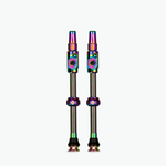 Two Muc-Off tubeless presta valves with rainbow iridescent finish on white background