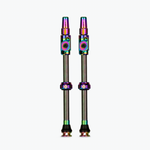 Two Muc-Off tubeless presta valves with iridescent rainbow finish on white background