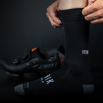 Person putting on black Gobik cycling socks with white logo branding