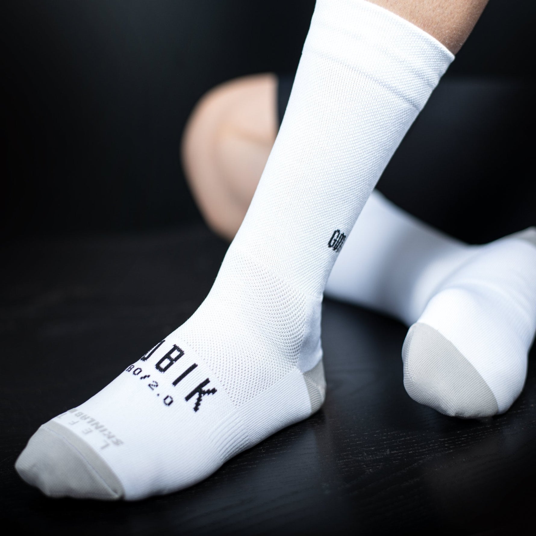 White Gobik Iro 2.0 cycling socks with black logo worn on feet