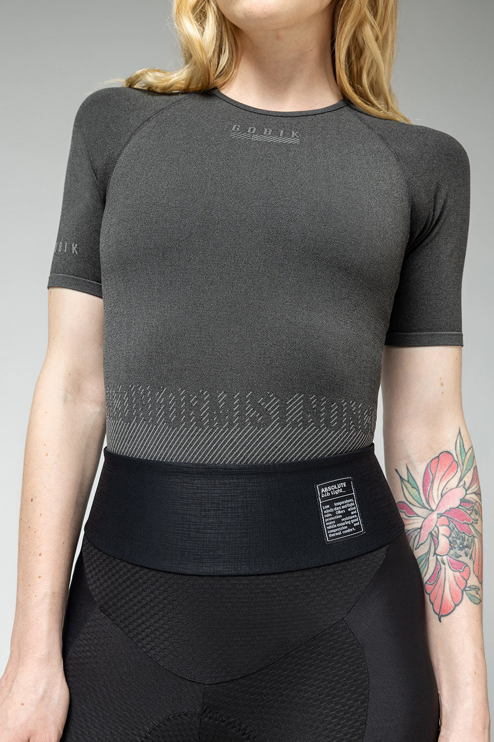 Woman wearing Gobik grey base layer top with textured pattern and black athletic wear