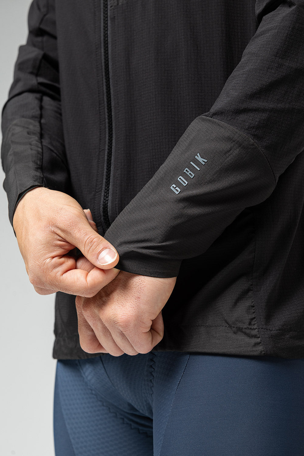 Man wearing black Gobik lightweight rain jacket with brand logo on sleeve