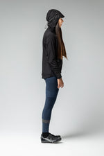 Woman wearing black Gobik lightweight rain jacket with hood and blue cycling leggings