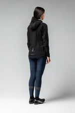 Woman wearing black Gobik lightweight rain jacket with hood, back view studio shot