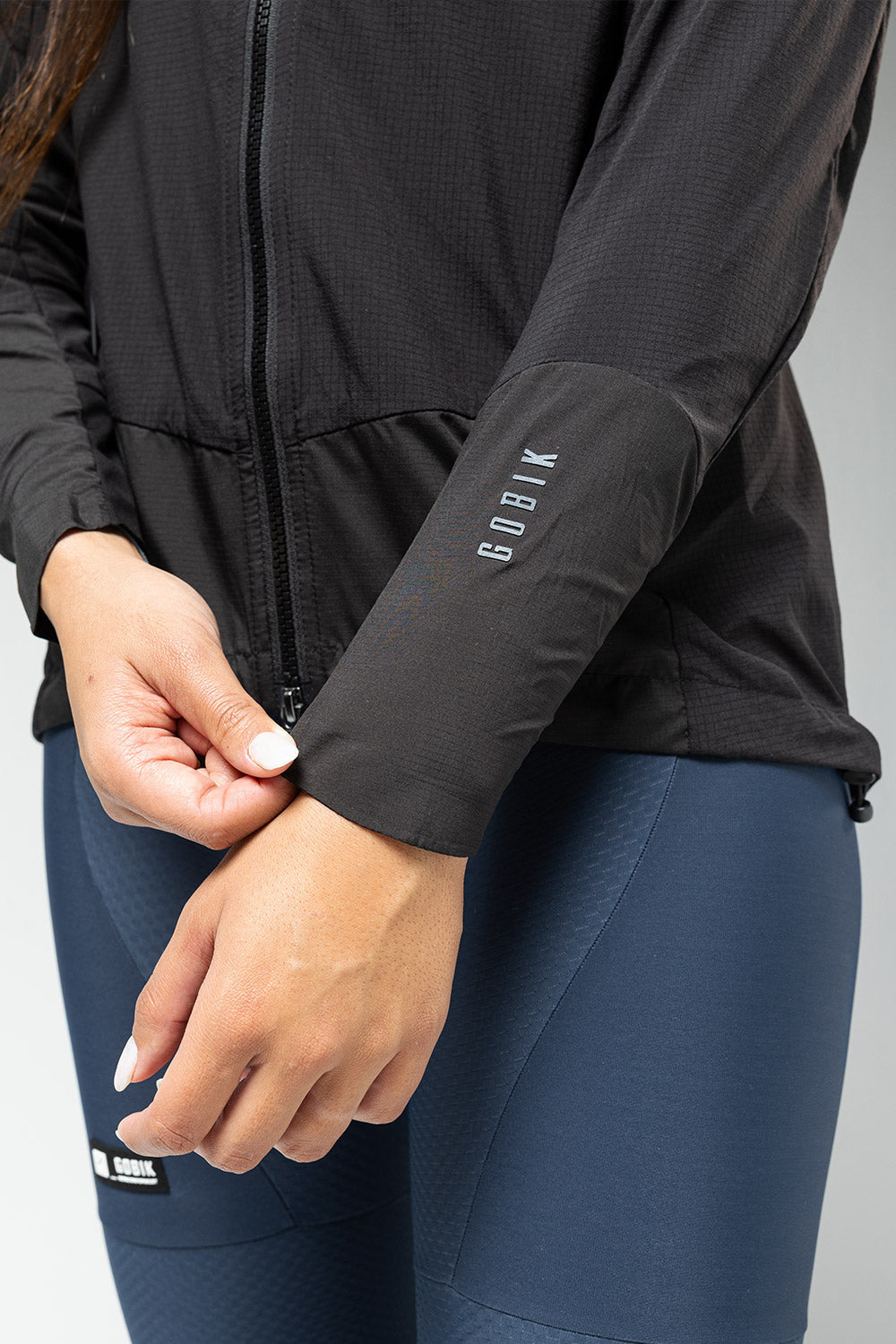 Woman wearing black Gobik lightweight rain jacket with zipper and sleeve branding