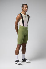 Male model wearing Gobik Matt 2.0 bib shorts in olive green with mesh base layer