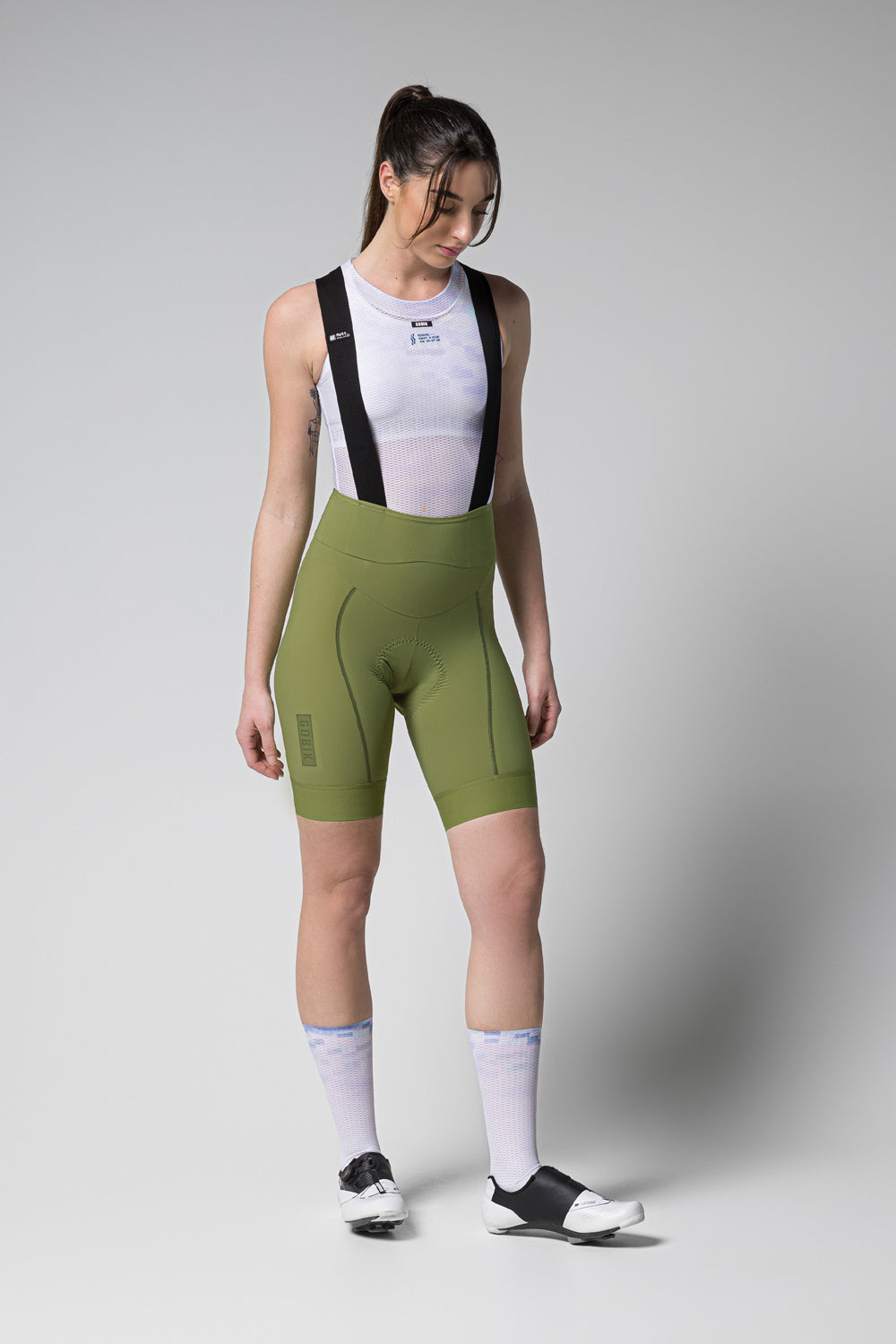 Woman wearing Gobik Matt 2.0 Bib Shorts in olive green with white mesh top