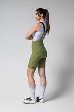 Woman wearing Gobik Matt 2.0 bib shorts in olive green with white jersey