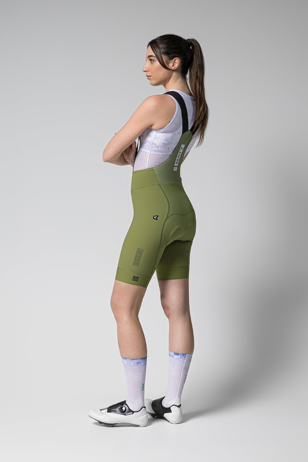 Woman wearing Gobik Matt 2.0 bib shorts in olive green with white jersey