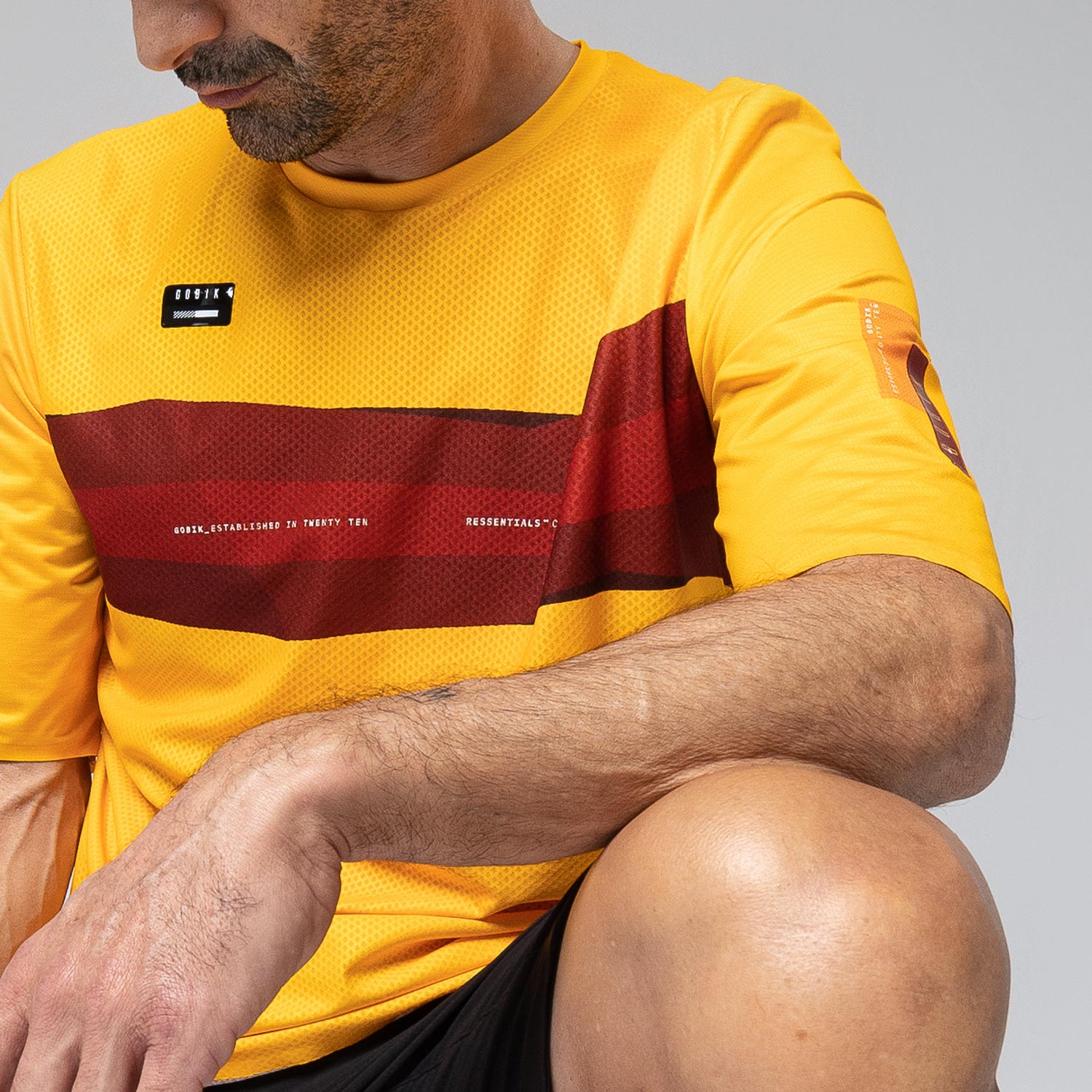Man wearing yellow Gobik Volt t-shirt with red stripes in studio setting