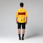 Back view of man wearing yellow Gobik Volt cycling jersey with red stripe