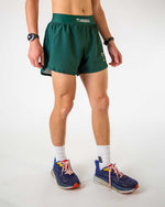 Man wearing ChicknLegs forest green running shorts with split hem design