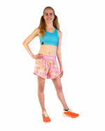 Woman wearing pink ChicknLegs split shorts with yellow duck pattern and blue sports bra