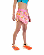Woman wearing pink ChicknLegs split running shorts with princess tiara pattern and teal sports bra