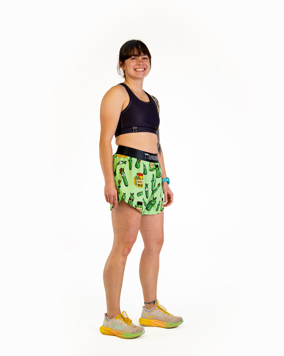 Woman wearing ChicknLegs green pickle patterned 4-inch split running shorts with sports bra