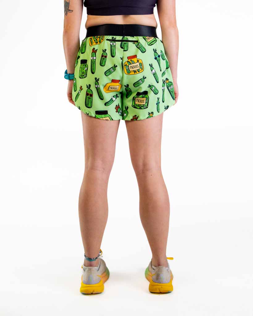 Woman wearing green pickle-patterned athletic shorts with black waistband, back view