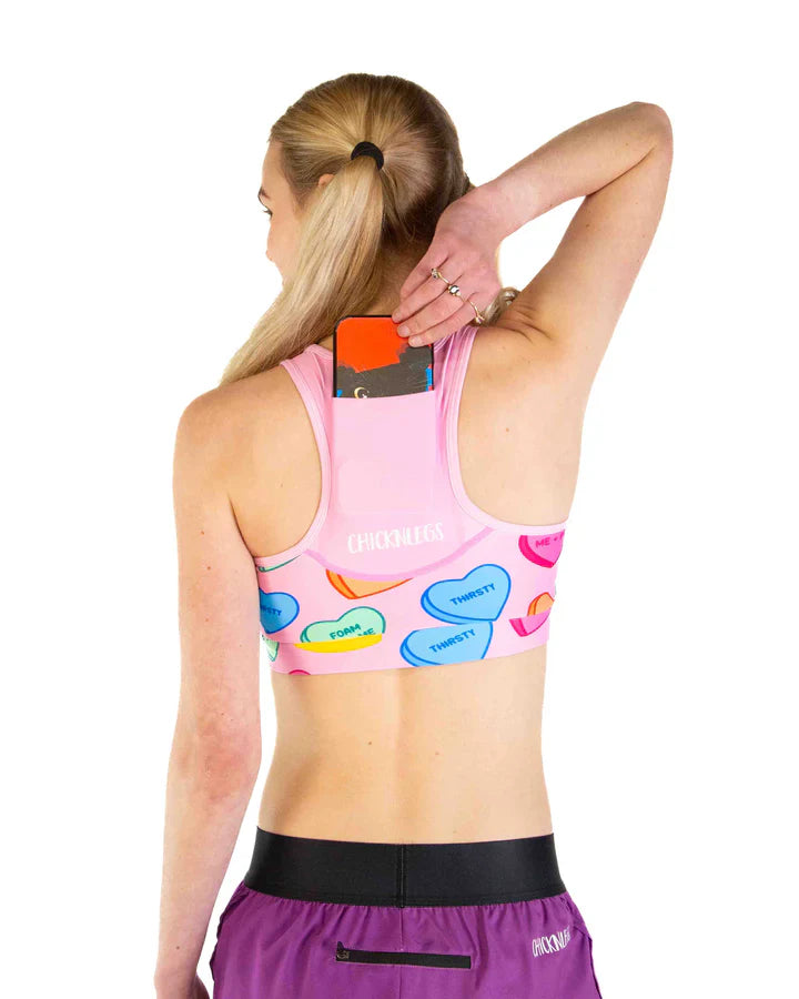 ChicknLegs pink sports bra with candy hearts pattern, back view showing phone pocket