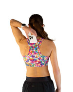 Woman wearing ChicknLegs tie-dye sports bra with colorful rainbow pattern, back view