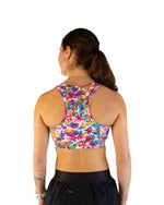 Back view of woman wearing ChicknLegs tie-dye sports bra with colorful rainbow pattern