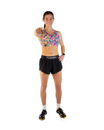 Woman wearing colorful tie-dye sports bra and black shorts in athletic pose