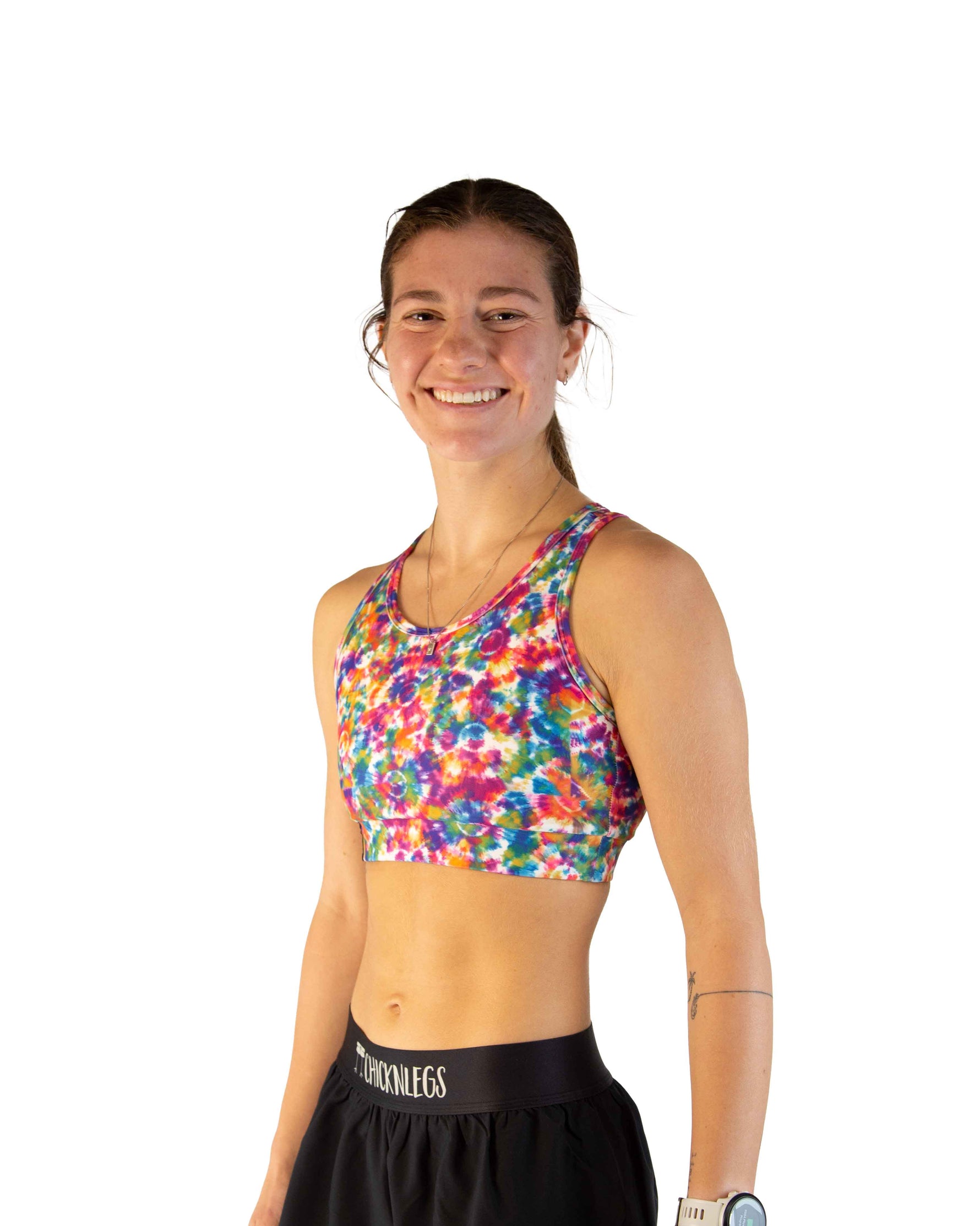 Woman wearing ChicknLegs tie-dye sports bra with colorful rainbow pattern and black shorts