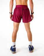 Man wearing maroon athletic shorts with split hem, back view showing fit