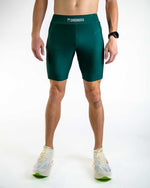 Man wearing ChicknLegs forest green compression shorts in studio setting