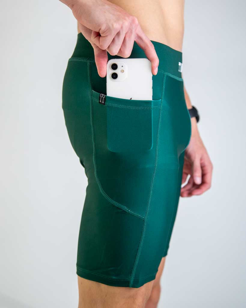 Man wearing forest green athletic shorts with phone in side pocket