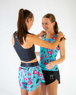 Two women wearing ChicknLegs turquoise flamingo print athletic wear with matching tops and shorts