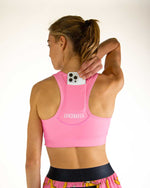 Woman wearing pink ChicknLegs sports bra with phone pocket, back view