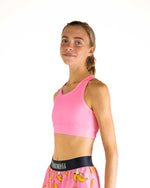 Woman wearing pink ChicknLegs sports bra with banana print shorts against white background