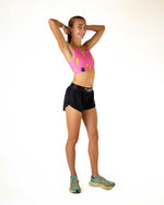 Woman wearing pink sports bra with yellow lightning bolts and black shorts