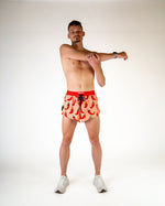 Man wearing ChicknLegs chili pepper print split shorts in coral with red pattern