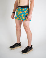 Man wearing ChicknLegs turquoise shorts with orange chicken nugget pattern and running shoes