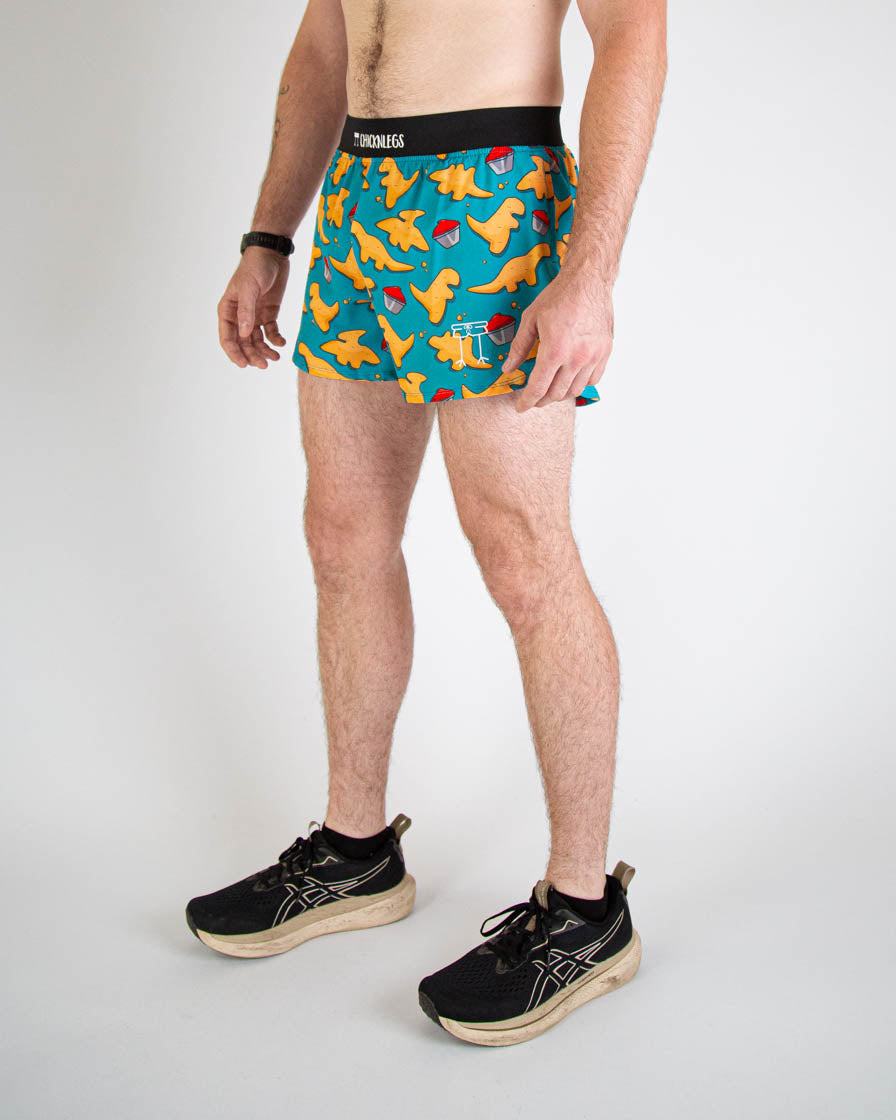Man wearing ChicknLegs turquoise shorts with orange chicken nugget pattern and black waistband