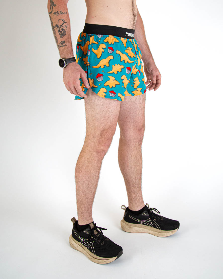 Man wearing teal running shorts with orange dinosaur and pokeball print pattern