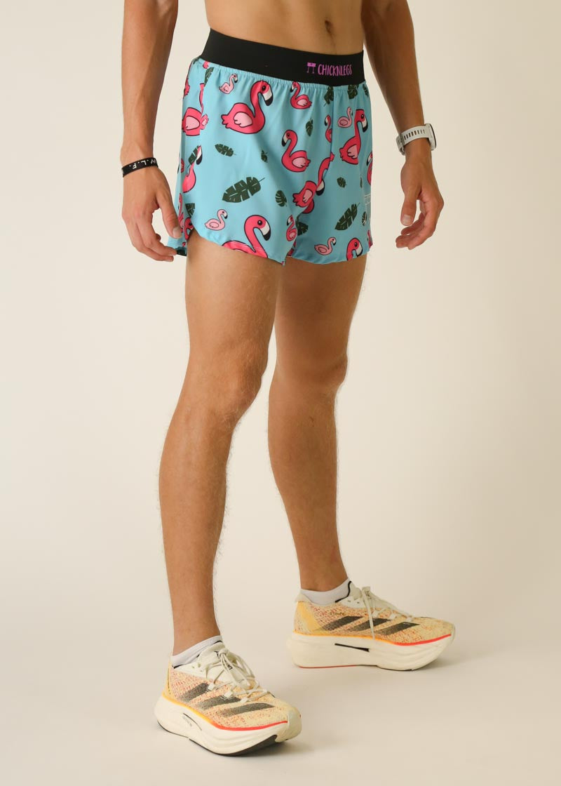 Man wearing light blue shorts with pink flamingo and tropical leaf pattern