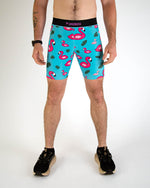 Man wearing turquoise blue compression shorts with pink flamingo and tropical leaf pattern