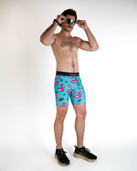 Man wearing turquoise ChicknLegs half tights with pink flamingo pattern and sunglasses
