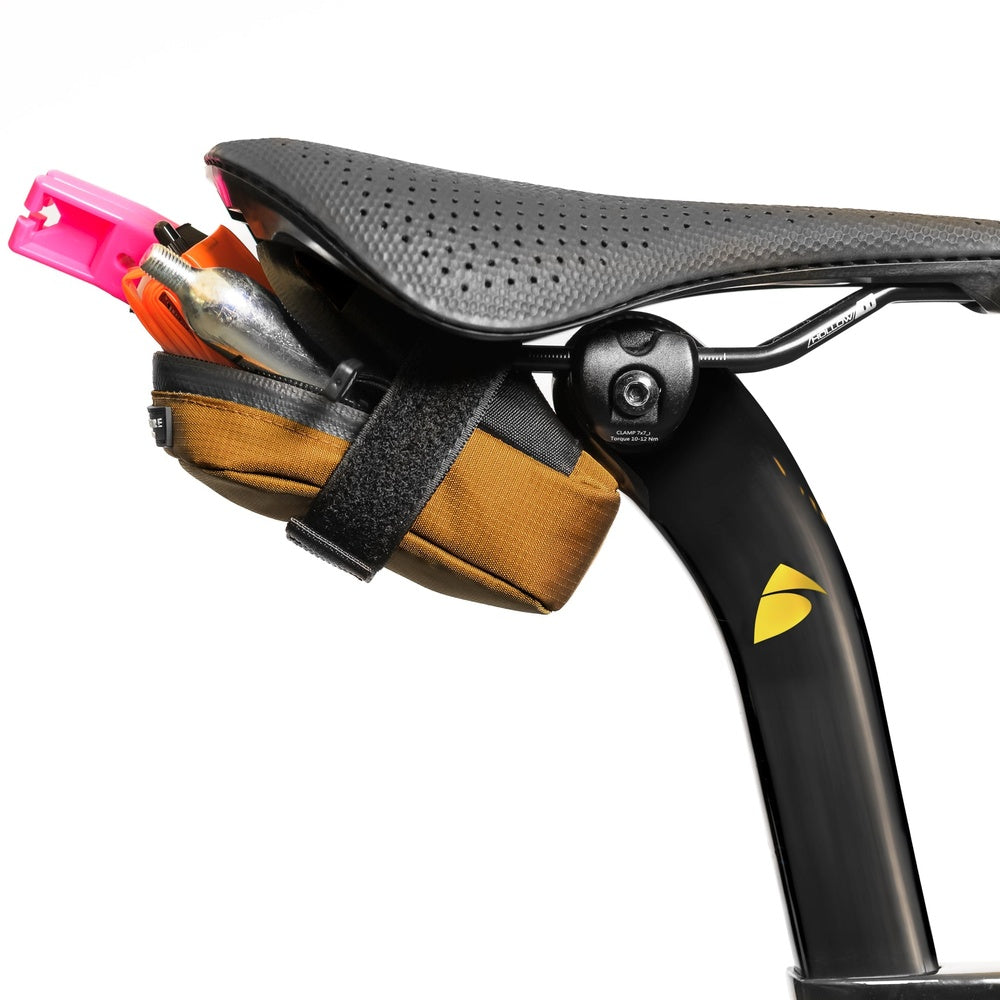Orange bicycle saddle bag attached to black seatpost with tool storage