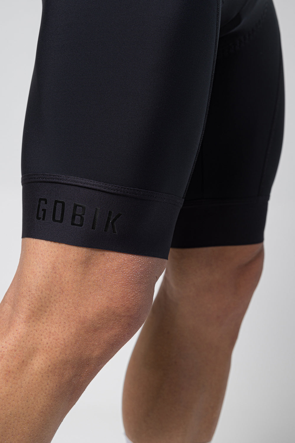 Close-up of black Gobik cycling bib shorts showing leg gripper with brand logo