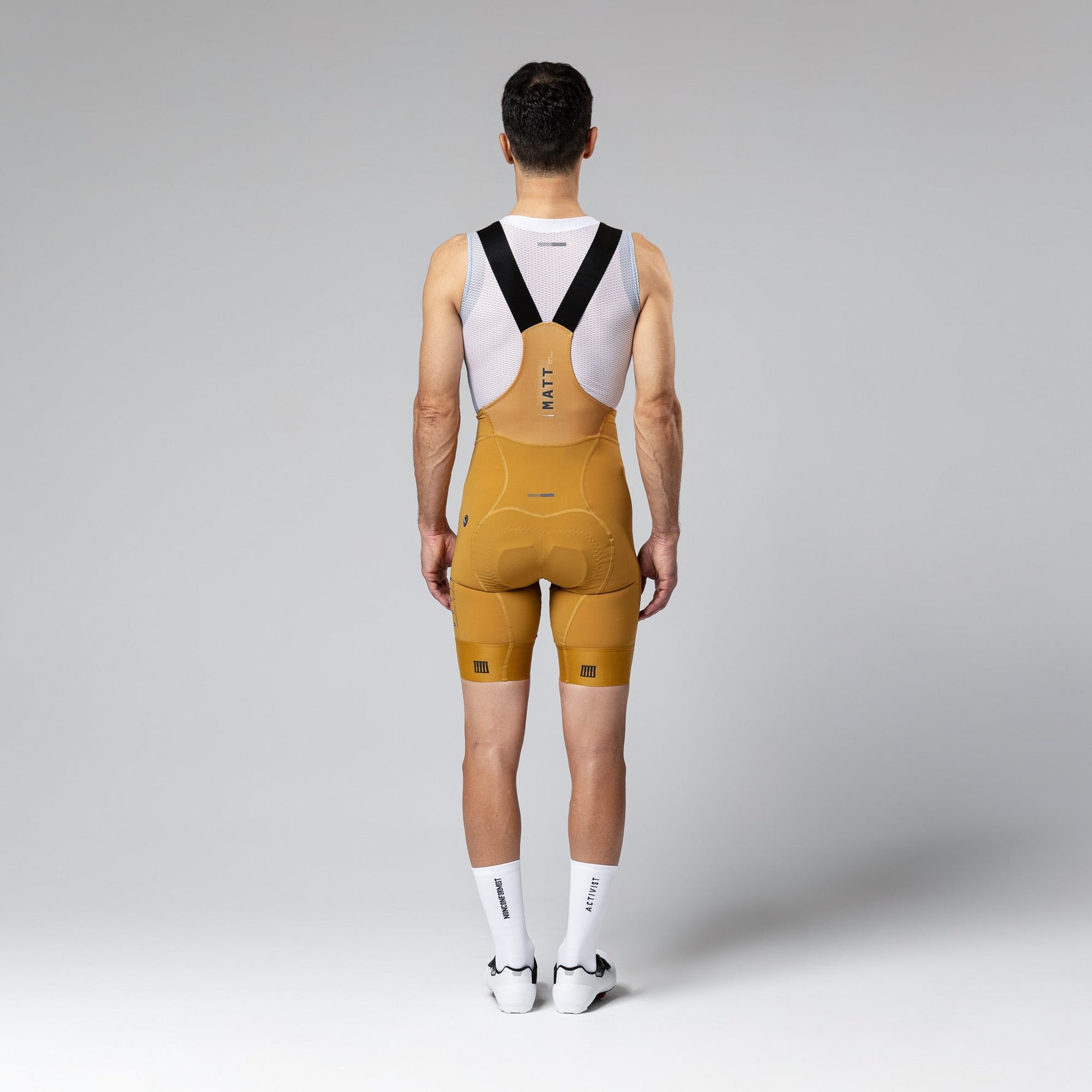 Gobik Matt Compact Men's Bibshorts in Turmeric yellow color, rear view showing suspender straps