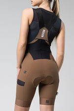 Woman wearing Gobik Grit bib shorts in toffee brown with black tank top