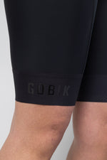 Close-up of black Gobik cycling bib shorts showing leg cuff with embossed branding