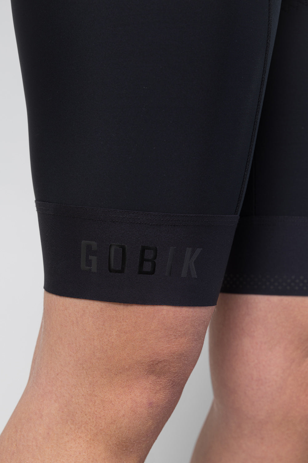 Close-up of black Gobik cycling bib shorts showing leg cuff with embossed branding