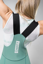 Woman wearing Gobik Matt Women's Bibshort in sage green with black straps